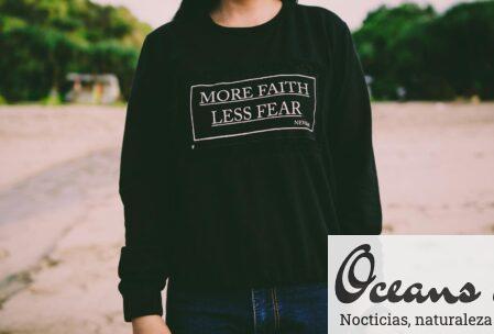 Close-up of a woman wearing a 'More Faith Less Fear' sweatshirt in an outdoor setting.