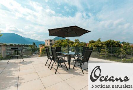 Spacious patio with seating and umbrella overlooking mountains and cityscape.