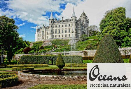 Explore the stunning Dunrobin Castle surrounded by manicured gardens and vibrant greenery under a blue sky.